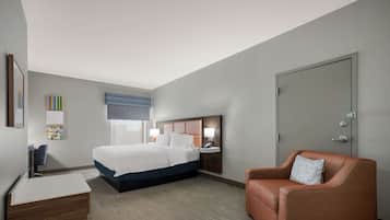 Una habitación de hotel con una cama, un escritorio, una silla y una puerta.