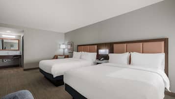 Une chambre d’hôtel avec deux lits, une salle de bain et un bureau avec une lampe.