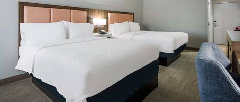 A hotel room with two beds, a desk, and a chair.