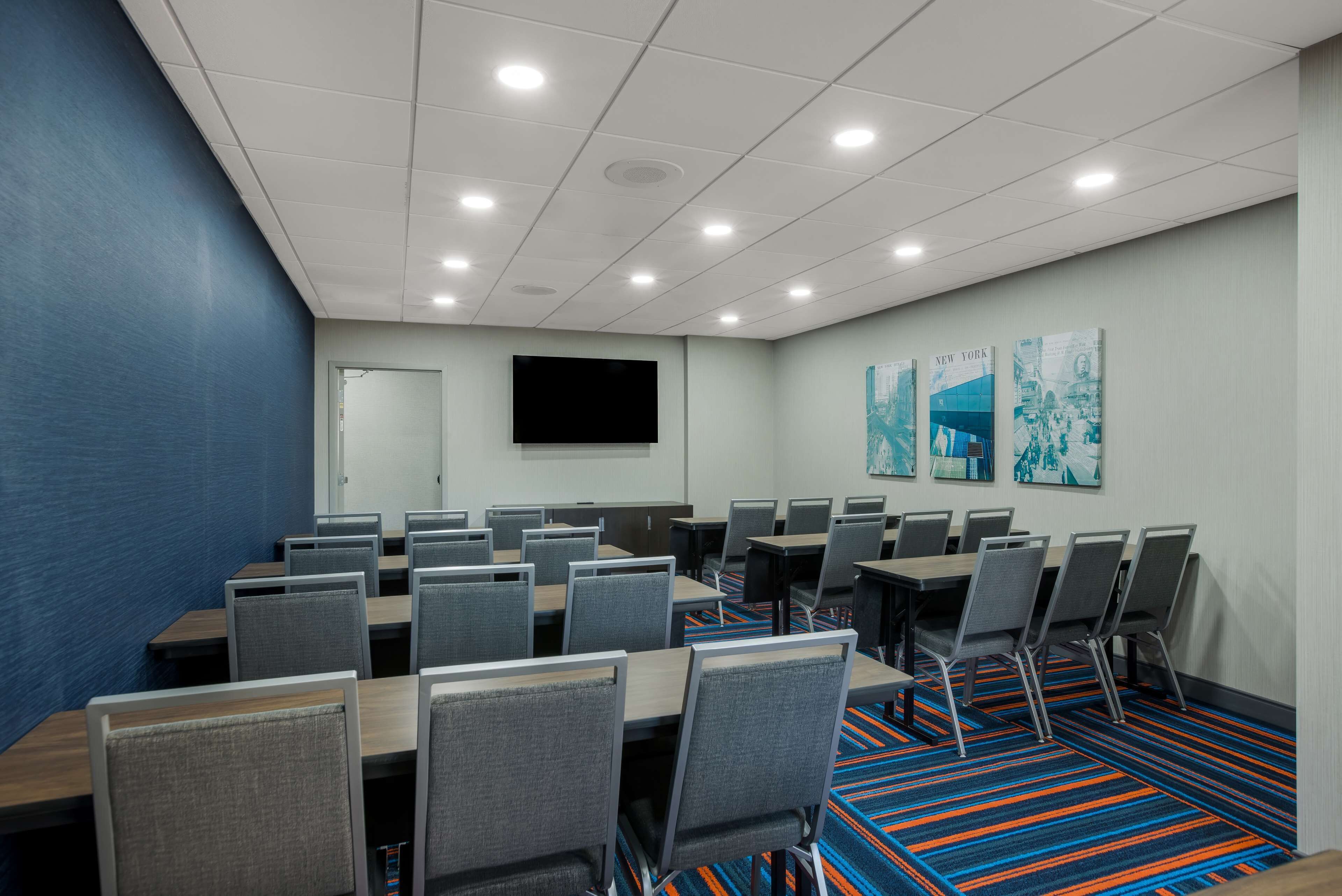 A conference room with multiple tables and chairs, a flat-screen TV, and artwork on the walls.