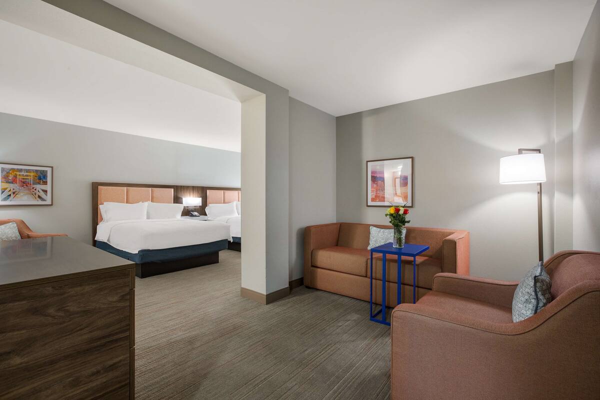 A hotel room with a bed, a desk, a sofa, and a small table with a vase of flowers.