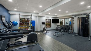 Un gimnasio con cintas de correr, pelotas de ejercicio y mancuernas.
