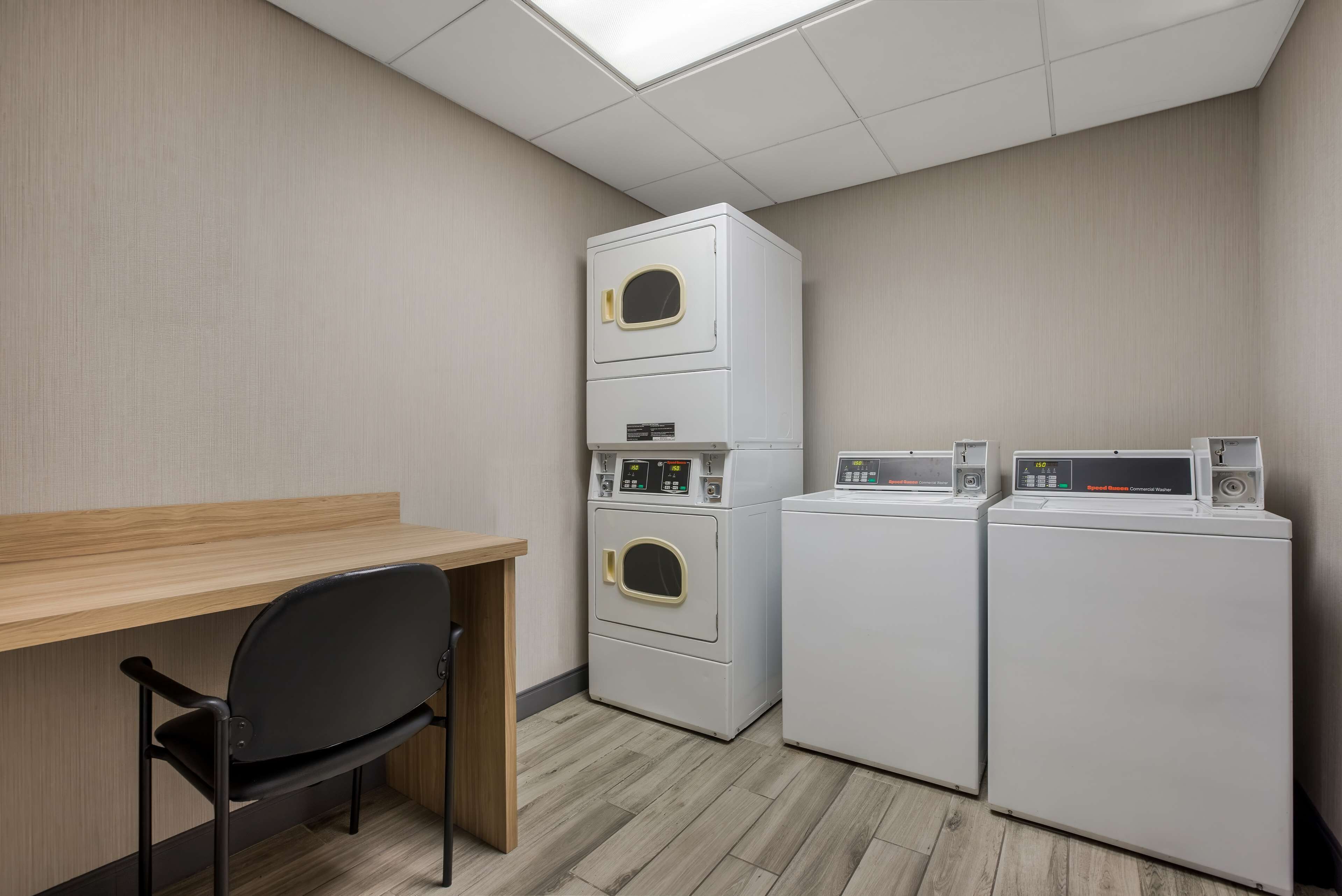 A laundry room with a wooden desk and two stacked washers and dryers.