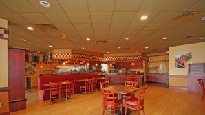 A restaurant interior with wooden flooring, red booths, and a central counter. - Suburban Studios Florence I-95 (Florence)