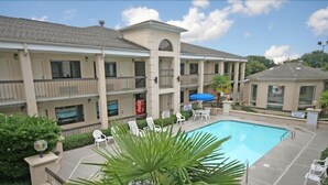 A hotel with a swimming pool, multiple balconies, and outdoor seating. - Suburban Studios Florence I-95 (Florence)