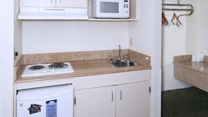 A compact kitchenette with a microwave, stove, and refrigerator. - Suburban Studios Florence I-95 (Florence)