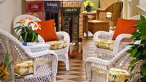 A cozy indoor seating area with wicker chairs, a checkered floor, and a decorative wall with a plant.