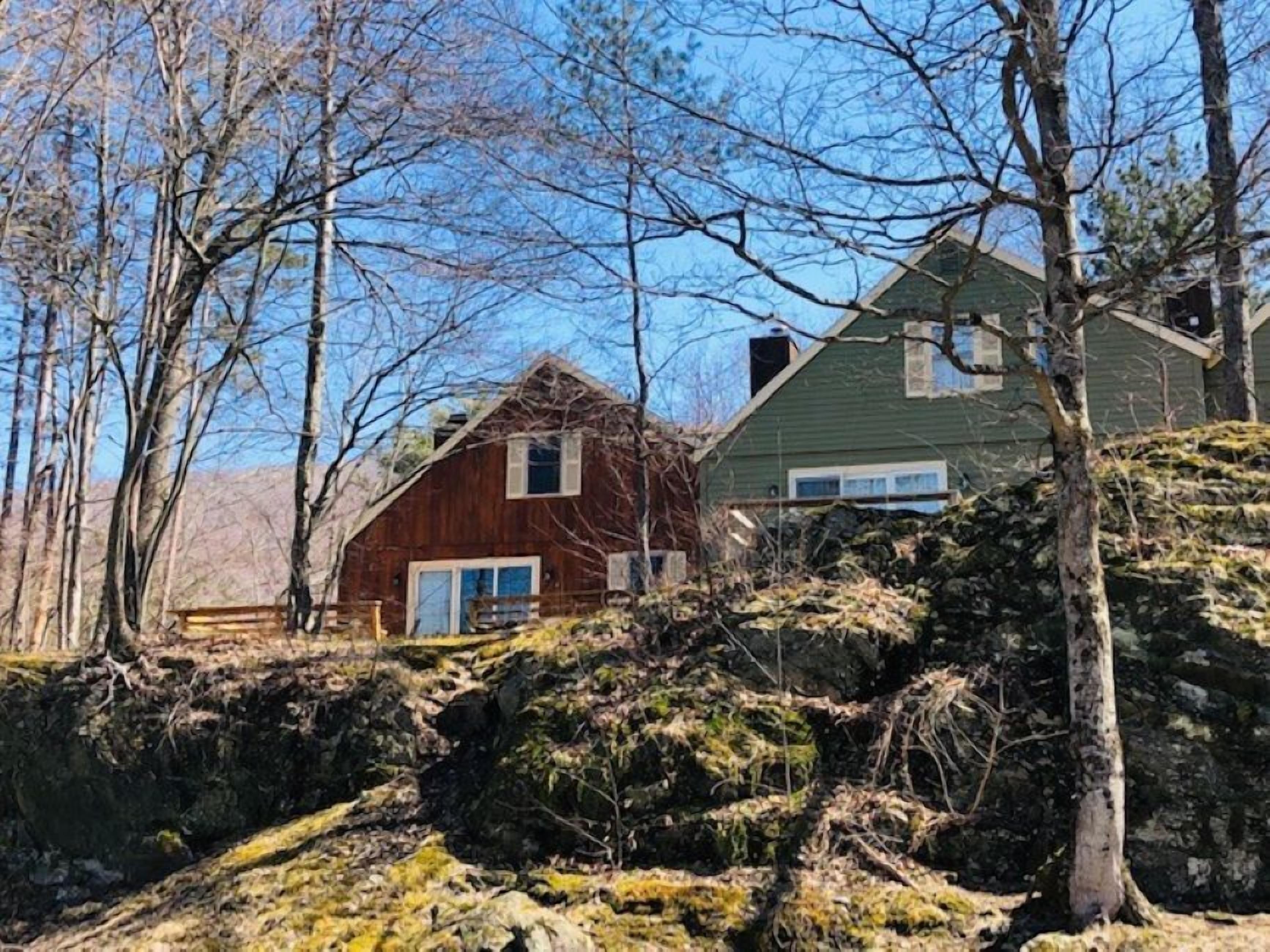 Eine rustikale Holzhütte mit Außenverkleidung aus Holz, umgeben von Bäumen und einer felsigen Landschaft.