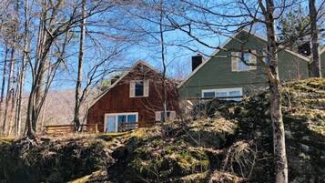 Eine rustikale Holzhütte mit Außenverkleidung aus Holz, umgeben von Bäumen und einer felsigen Landschaft.