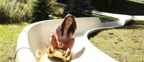 Une personne sur une luge jaune, en haut d’une glissade courbe.