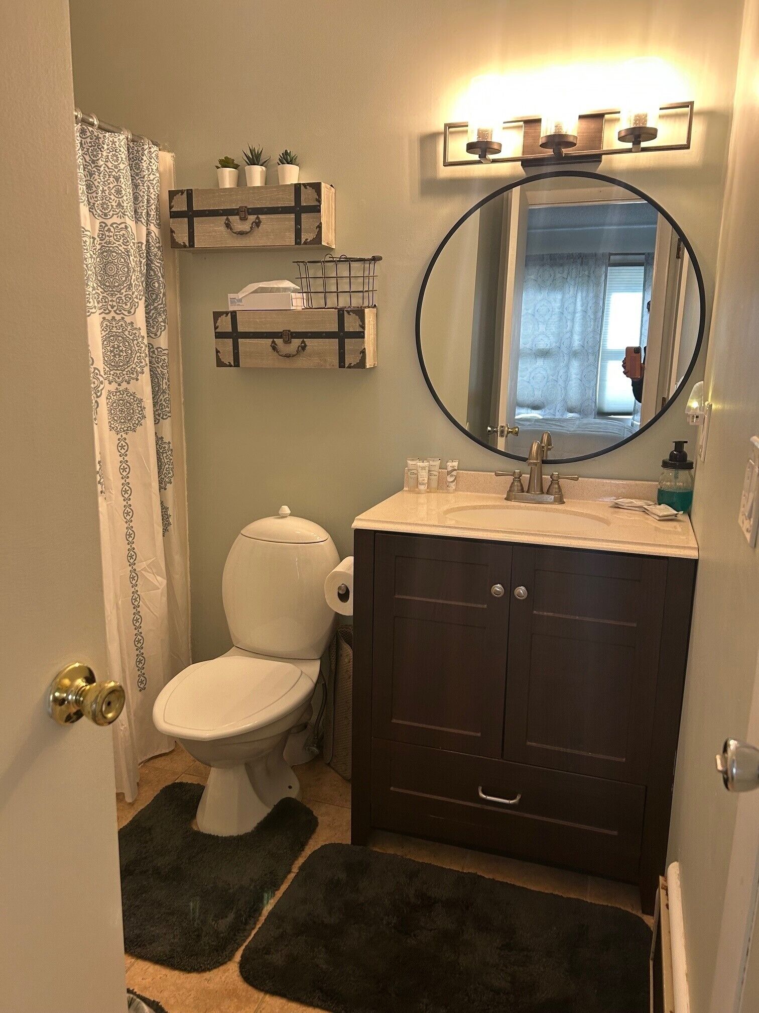 A bathroom with a toilet, a vanity with a mirror, and a shower curtain.
