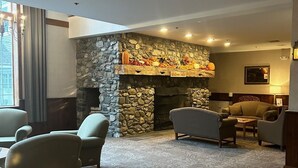 A cozy living room with a stone fireplace, comfortable seating, and a welcoming sign. - Jiminy Peak Mountain Resort (Hancock)