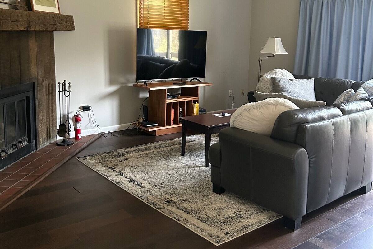 Uma sala de estar com lareira, televisão, sofá e mesa de centro.