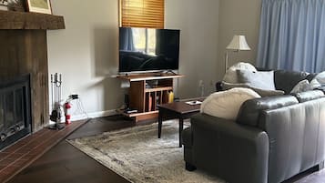Una sala de estar con chimenea, televisor, sofá y mesa de centro.