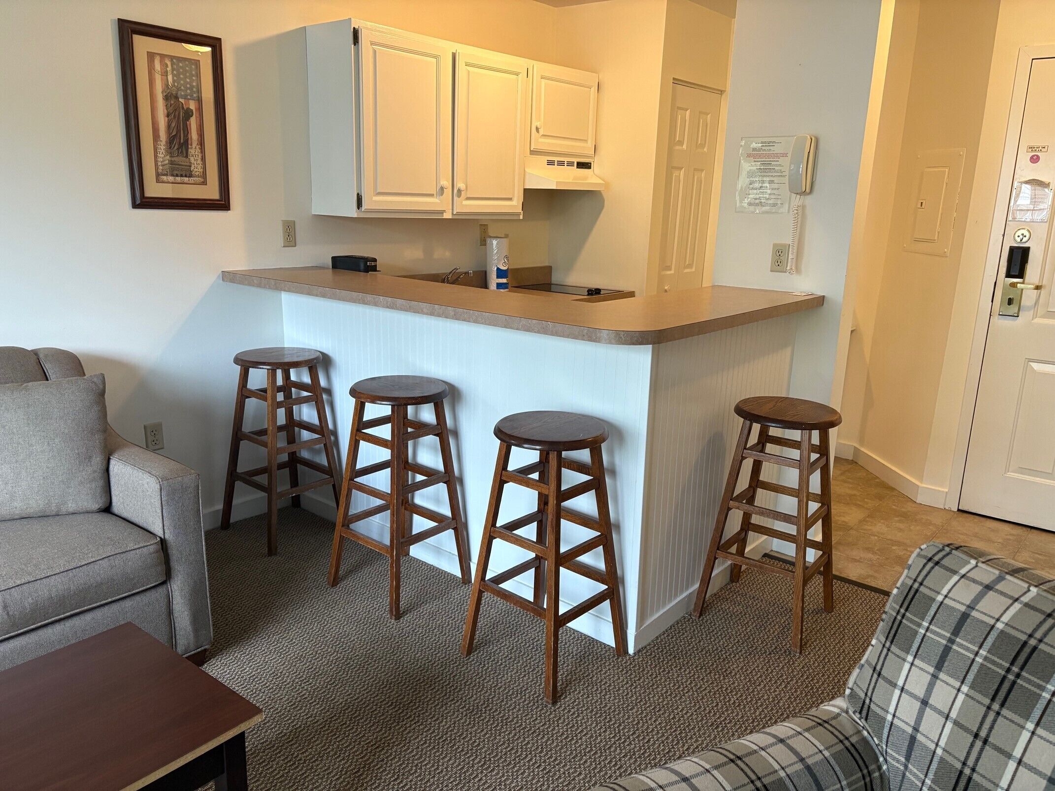 A compact living space with a kitchenette, a sofa, a dining table, and a bar stool area.