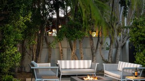 Une terrasse extérieure avec un foyer, deux canapés et une table.