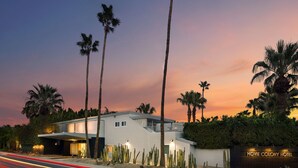 Un hôtel moderne doté d’un toit plat, de palmiers et d’un jardin désertique agrémenté de cactus.