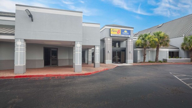 A modern building with a sign for 'Super 8 Conference Center' and a parking lot. - Super 8 by Wyndham Mobile I-65 (Mobile)