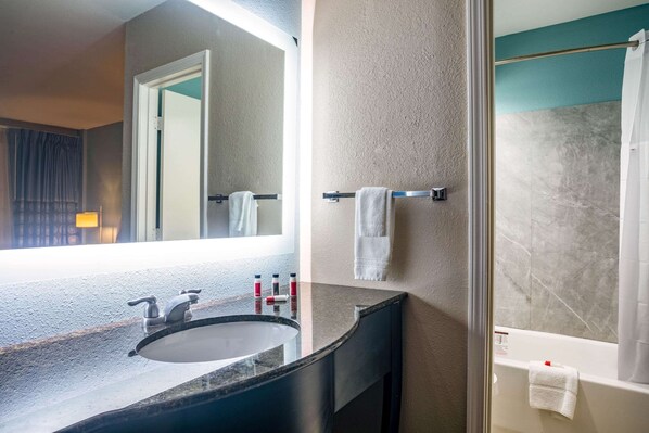 A bathroom with a sink, mirror, towel rack, and bathtub.