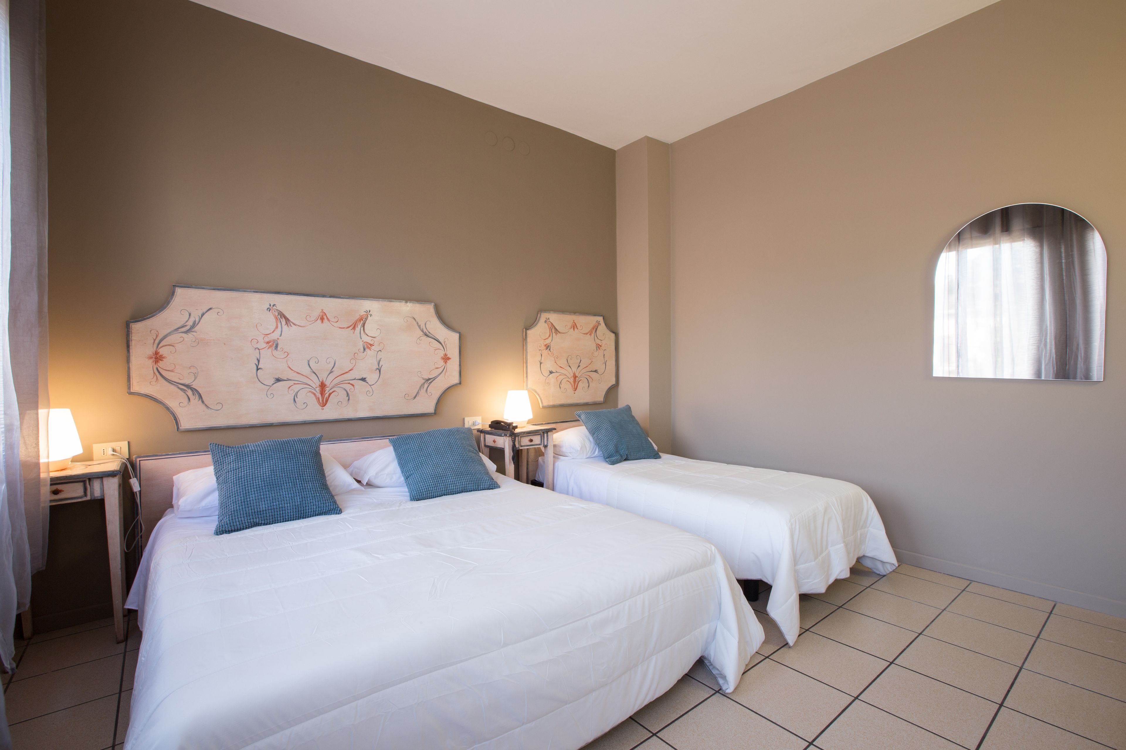 Una habitación de hotel con dos camas, una mesita de noche con lámpara y un adorno en la pared.