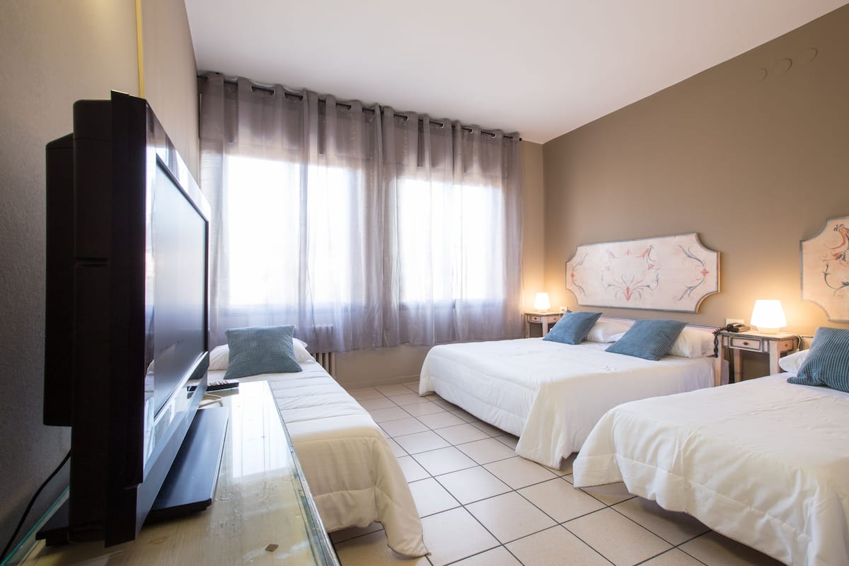 A hotel room with two beds, a TV, and a window with curtains.