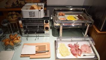 A buffet setup with various food items including bread, eggs, and meats.