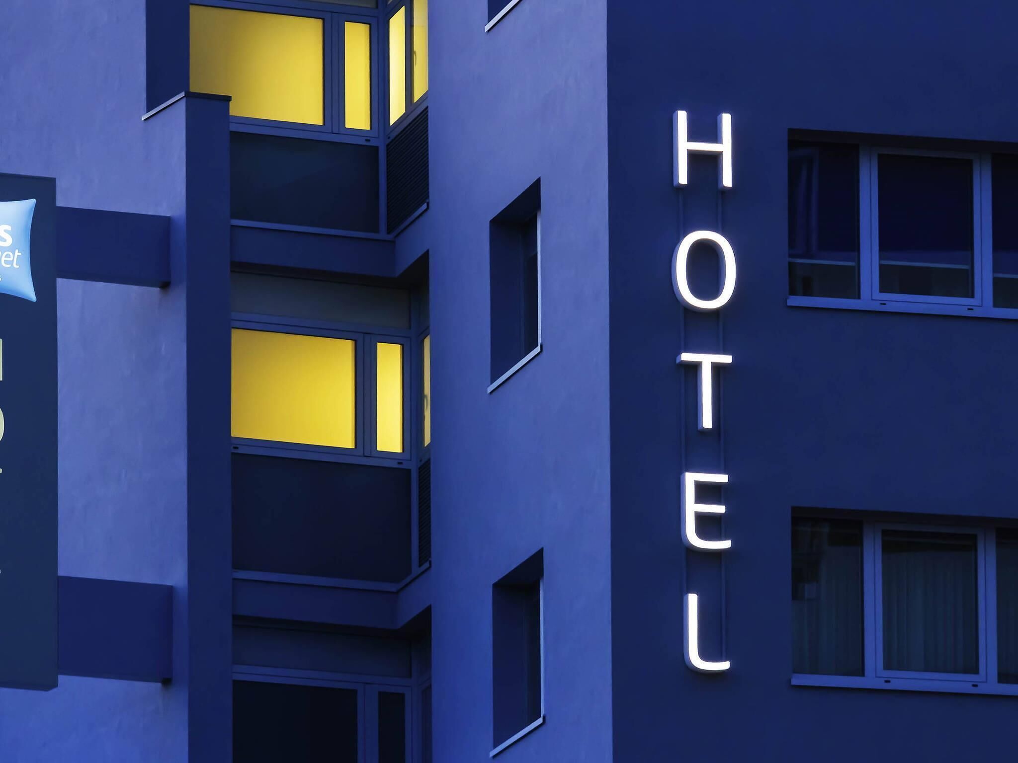 A hotel building with illuminated 'HOTEL' sign, multiple balconies, and windows.