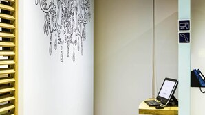 A modern office space with a desk, computer, and a blue stool. - ibis budget Braga Centro (Braga)
