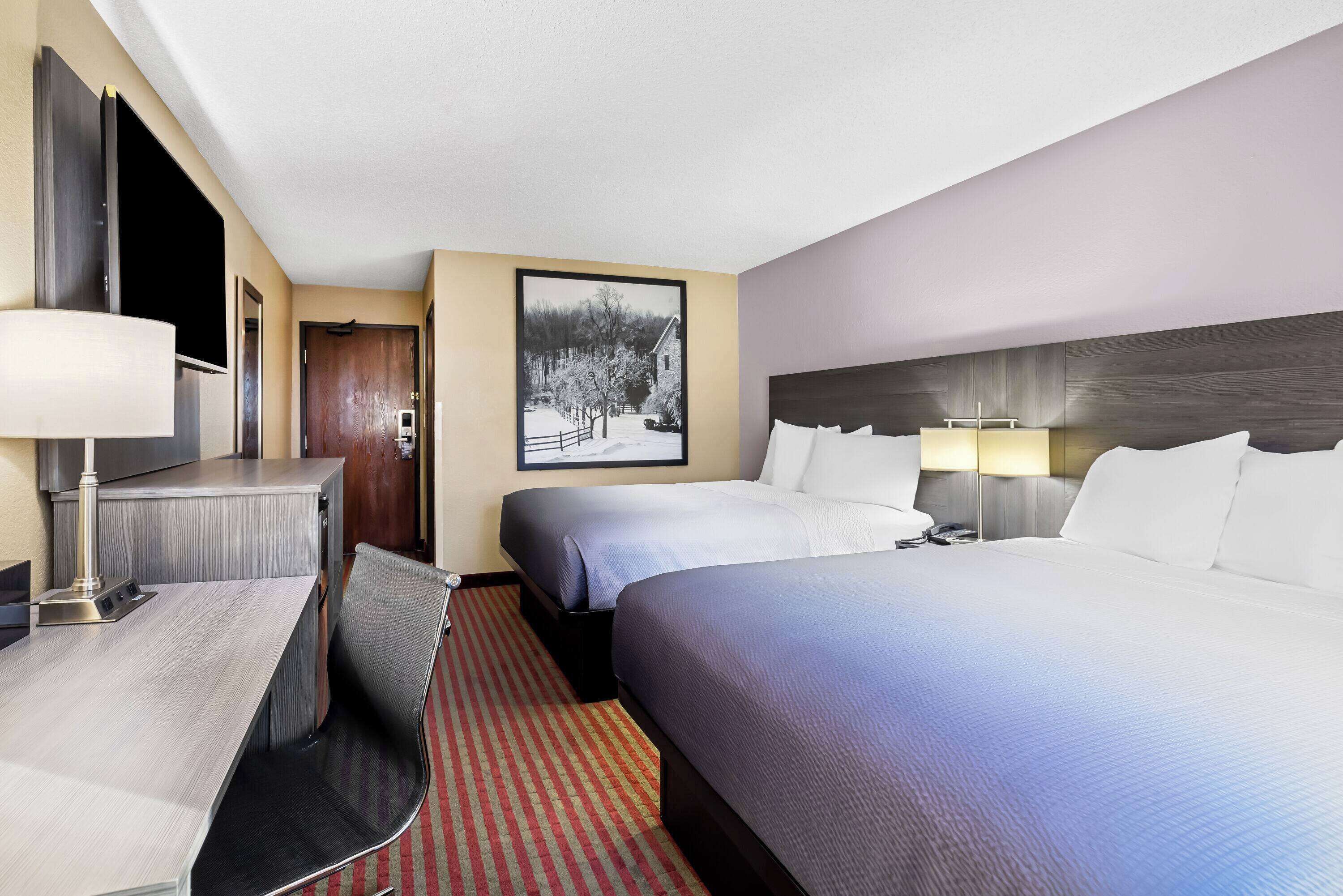 Een hotelkamer met twee bedden, een bureau, een stoel en een televisie.