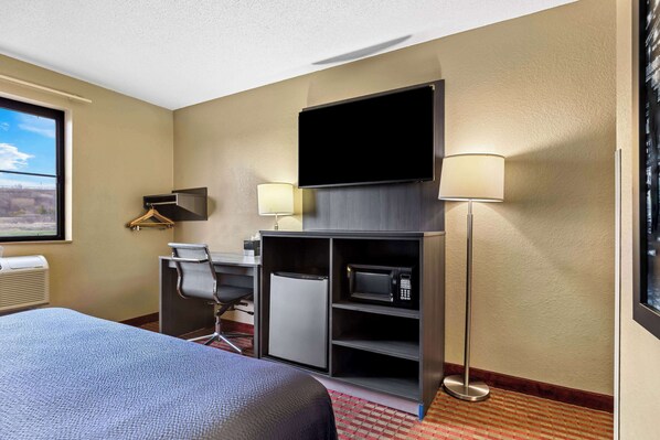 A hotel room with a bed, desk, chair, television, and microwave. - Super 8 by Wyndham Amsterdam (Amsterdam)