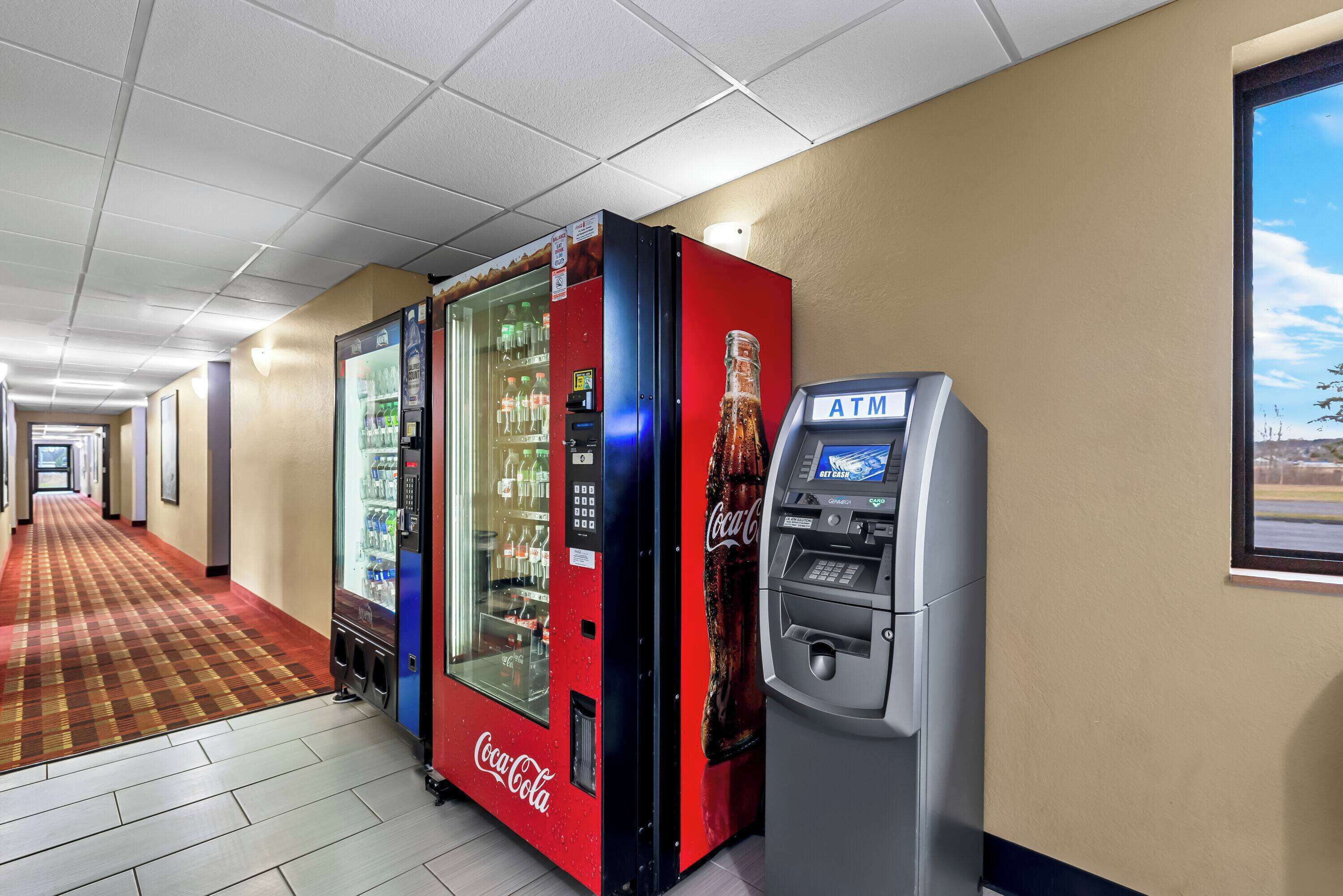 A hotel corridor with a Coca-Cola vending machine and an ATM.