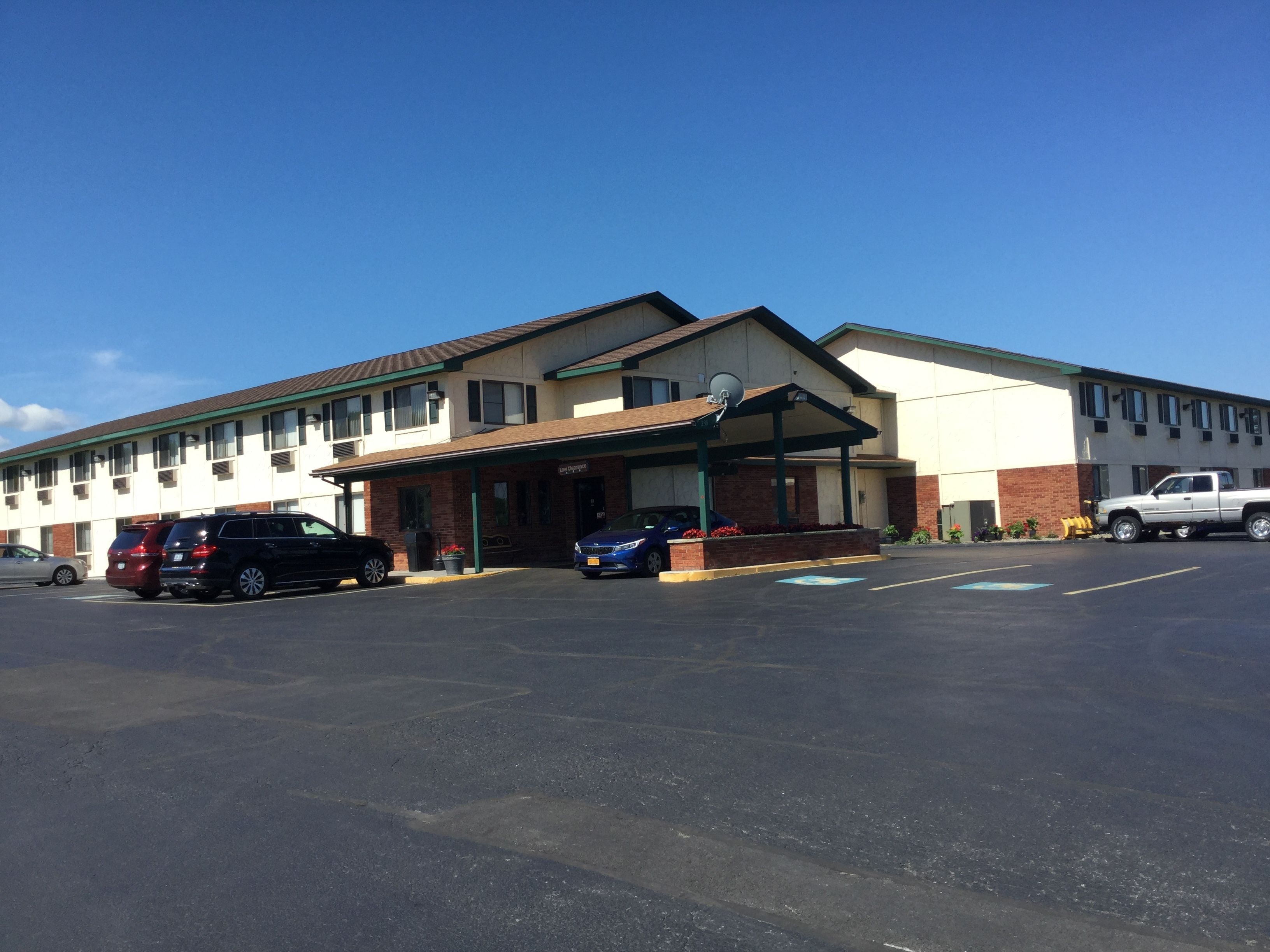 Un motel doté d’un parking couvert et d’un bâtiment comportant de nombreuses fenêtres et une antenne parabolique.