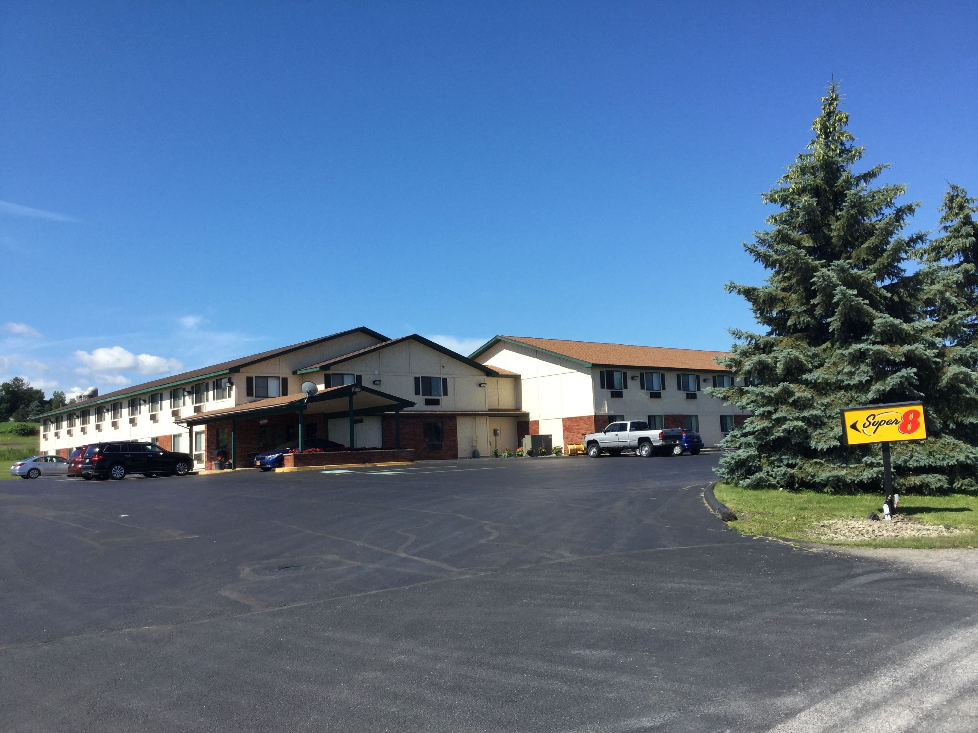 A motel with a parking lot, a covered entrance, and a sign for 'Super 8' hotel.