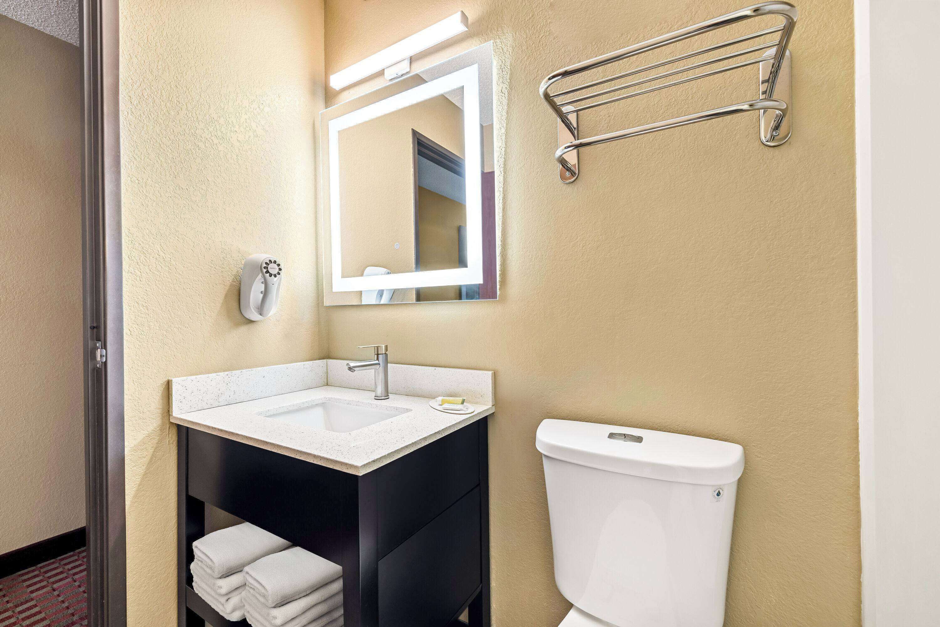 A bathroom with a white sink, a mirror, a towel rack, and a toilet.