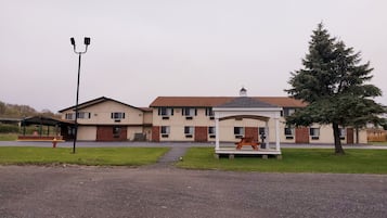 Een tweelaags gebouw met een overdekte buitenruimte en een pergola.