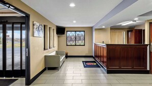 A hotel lobby with a reception desk, seating area, and a large window offering a view.