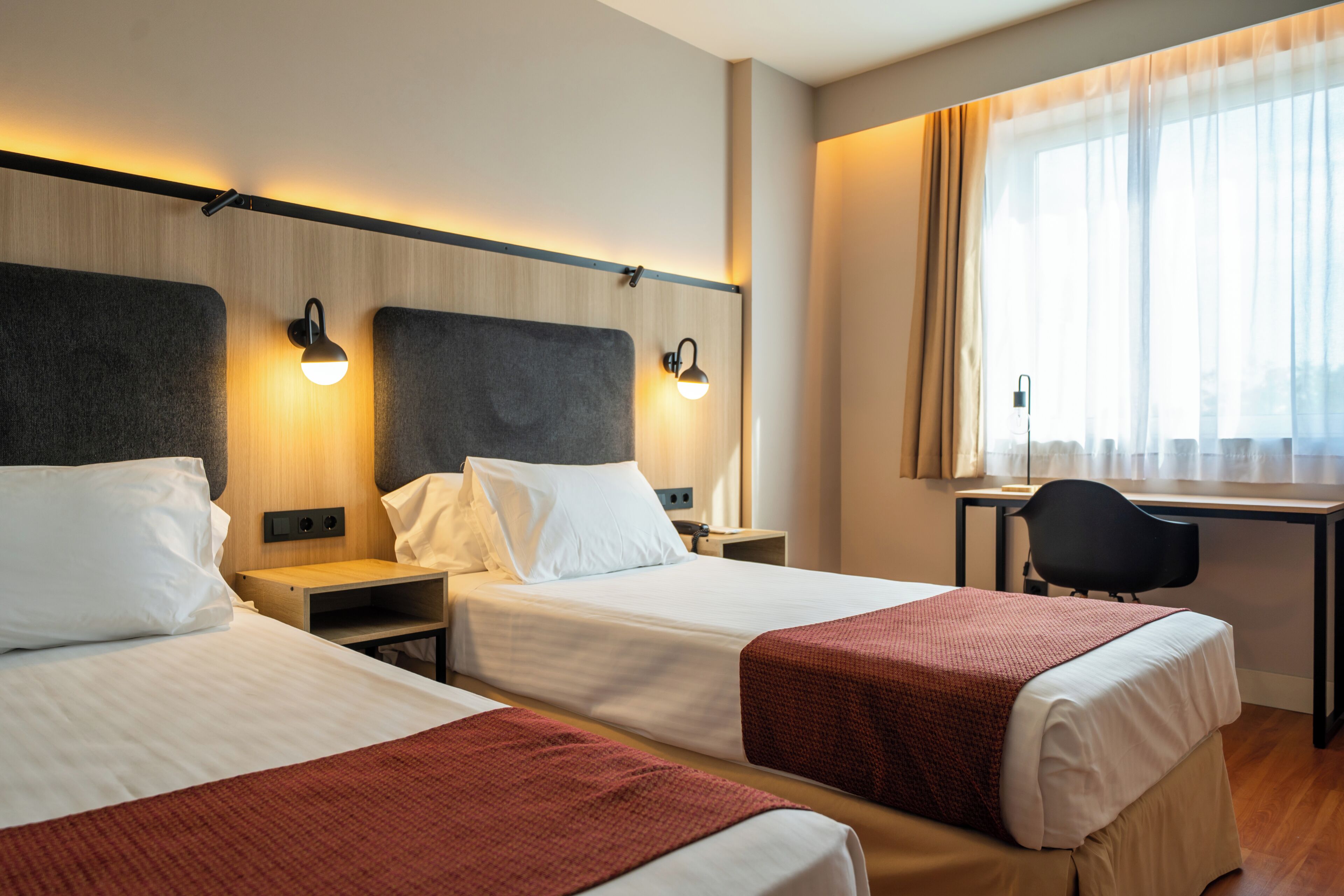 Habitación de hotel con dos camas, un escritorio y una silla.