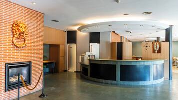 A reception area with a brick wall, a fireplace, a reception desk, and a clock.