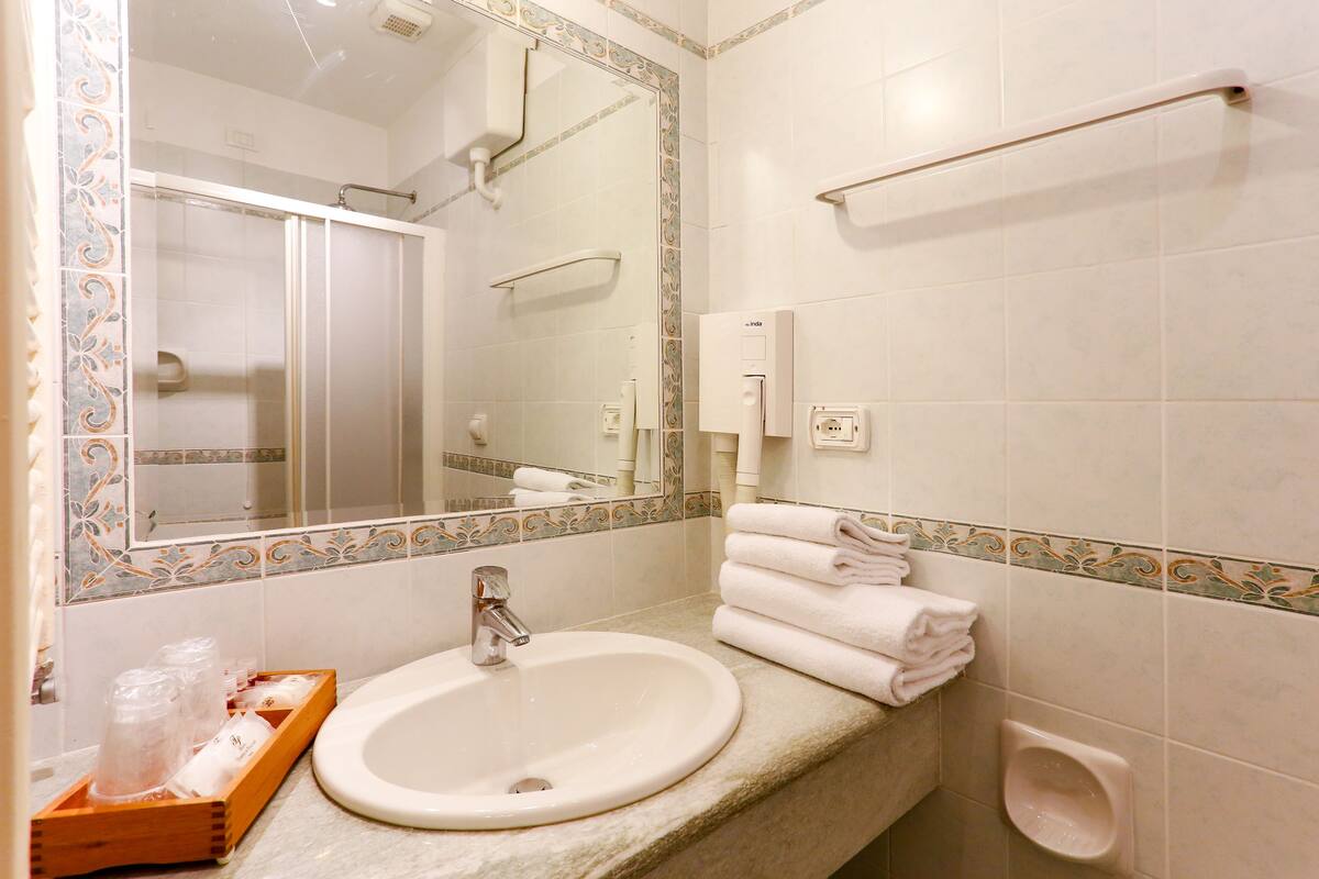 A bathroom with a sink, mirror, towel rack, and toilet.