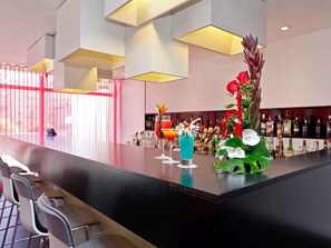 A bar area with a long counter, bar stools, and a decorative plant. - Mercure Braga Centro (Braga)
