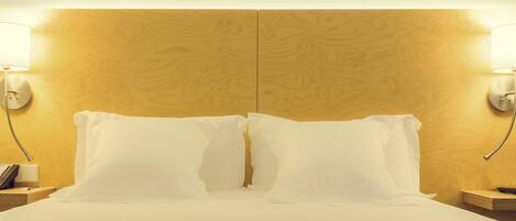A hotel room with a large bed, two bedside lamps, and a wooden headboard.