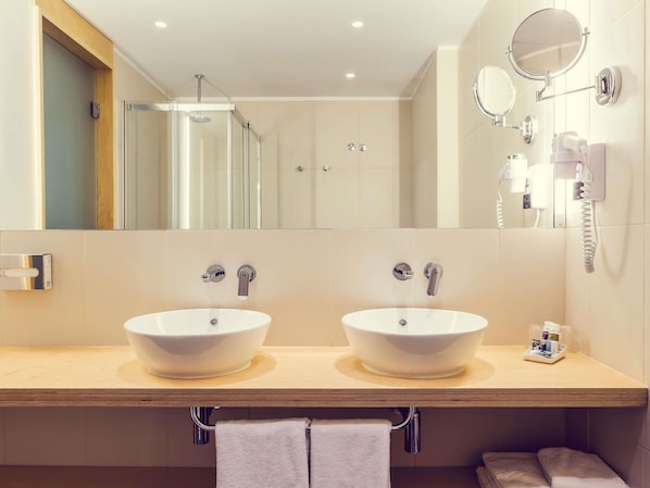 Un baño con dos lavamanos, ducha y espejo.