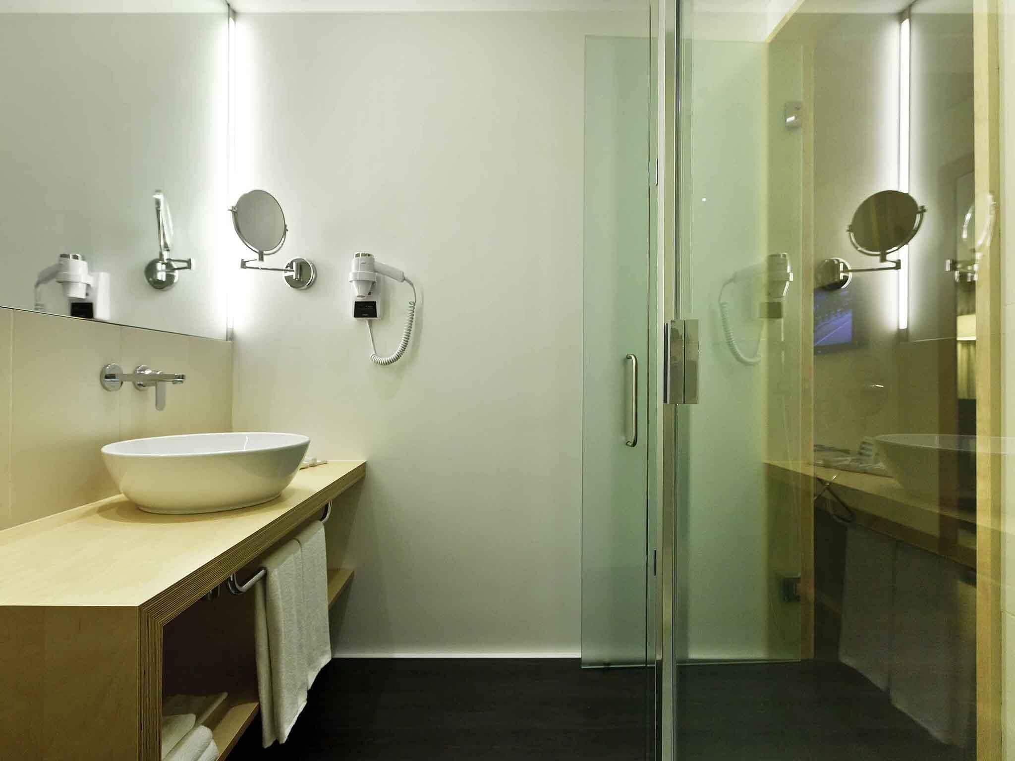 Un baño moderno con un lavamanos grande de color blanco, una cabina de ducha de vidrio y un espejo sobre el lavamanos.