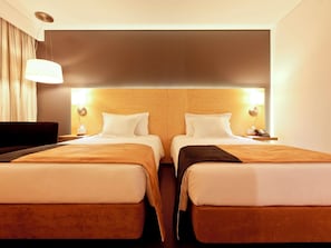 A hotel room with two beds, a dark headboard, bedside lamps, and a hanging light fixture. - Mercure Braga Centro (Braga)