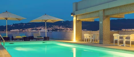 Una piscina al aire libre de temporada, sombrillas