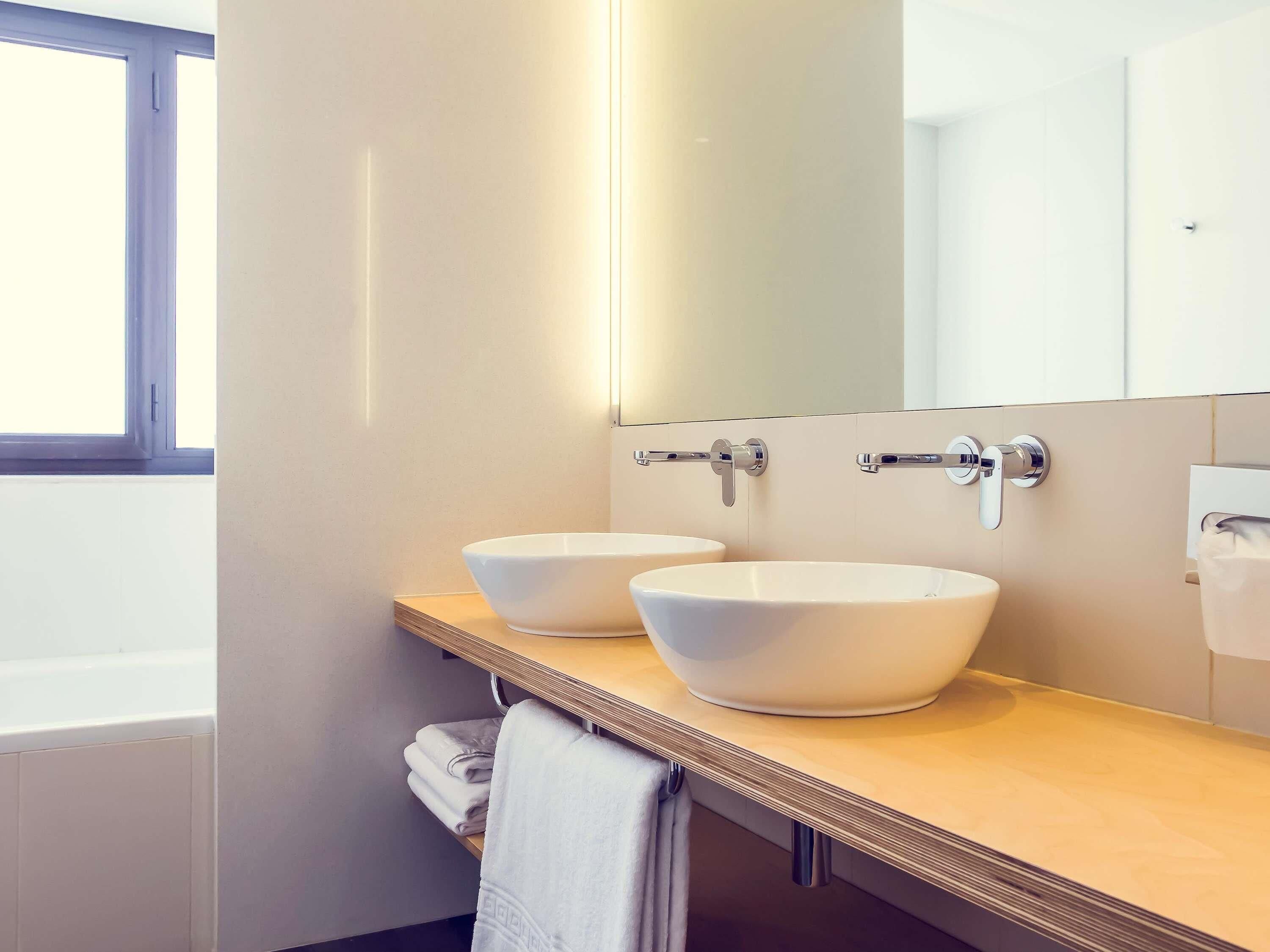 A bathroom with two white sinks, a wooden vanity, a towel rack, and a large mirror.