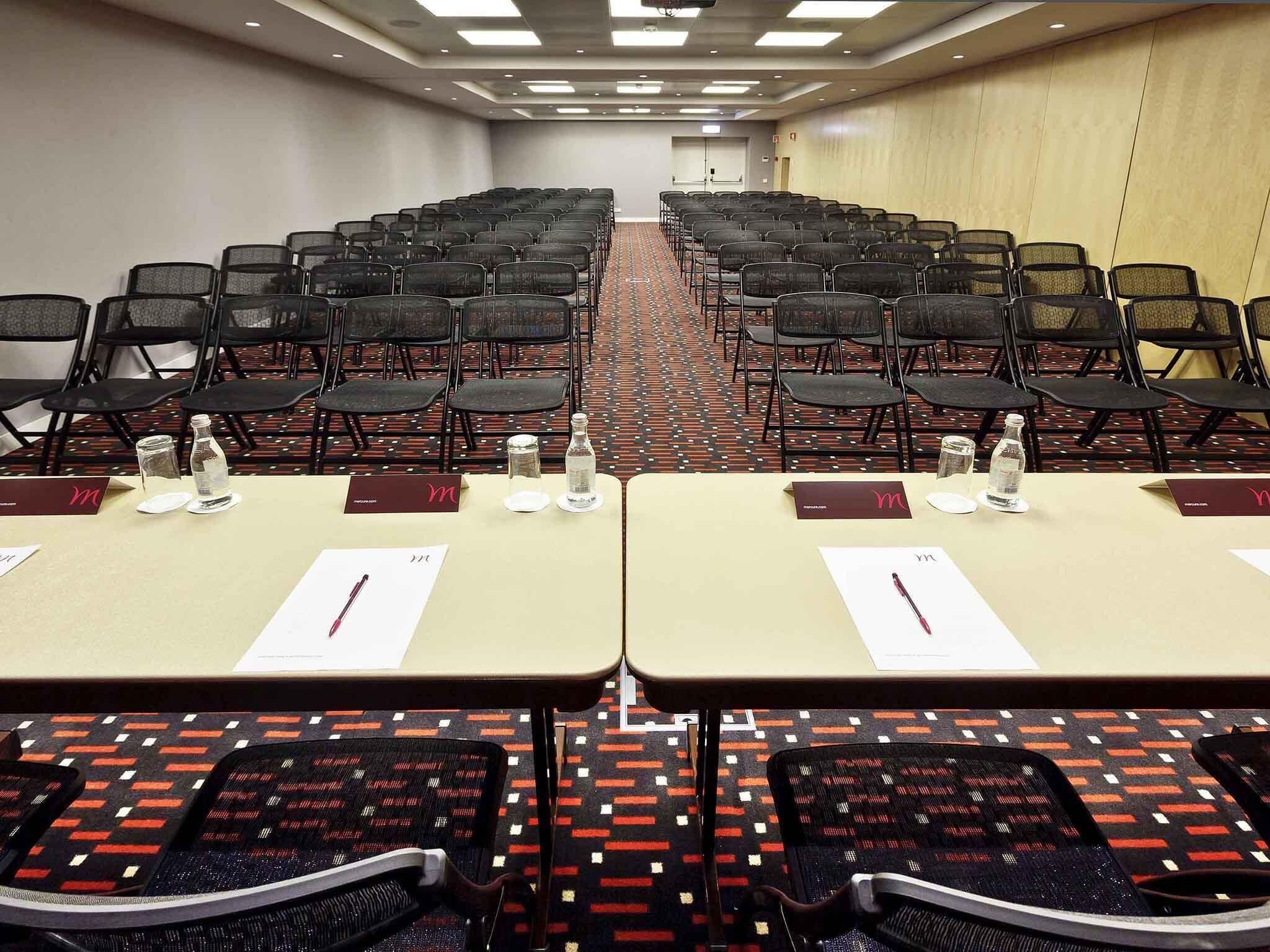 A conference room with rows of chairs and tables, each with a nameplate and water bottle.