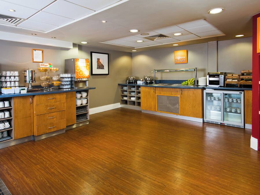 A modern kitchen area with a coffee station, a refrigerator, and a display of food items.