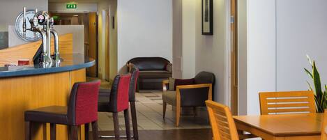 A hotel lobby with a reception desk, bar, seating area, and a framed picture on the wall.