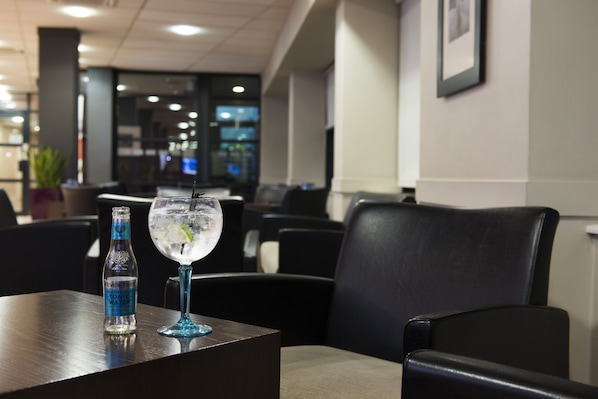 A restaurant setting with a table, chairs, and a glass of water with a bottle beside it.